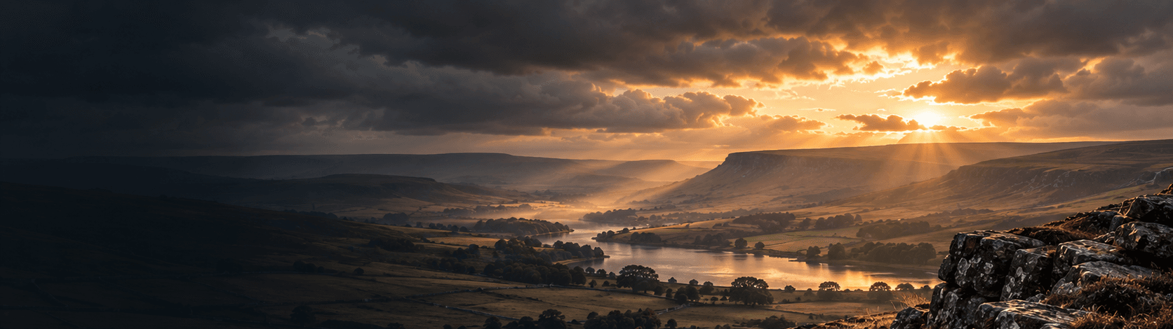 Sunlit valley and lake beneath breaking cloud